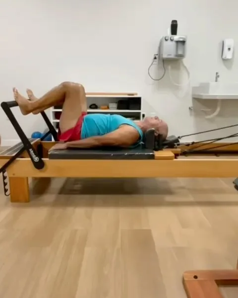 Paciente deitado no aparelho reformer de Pilates durante uma sessão na clínica.